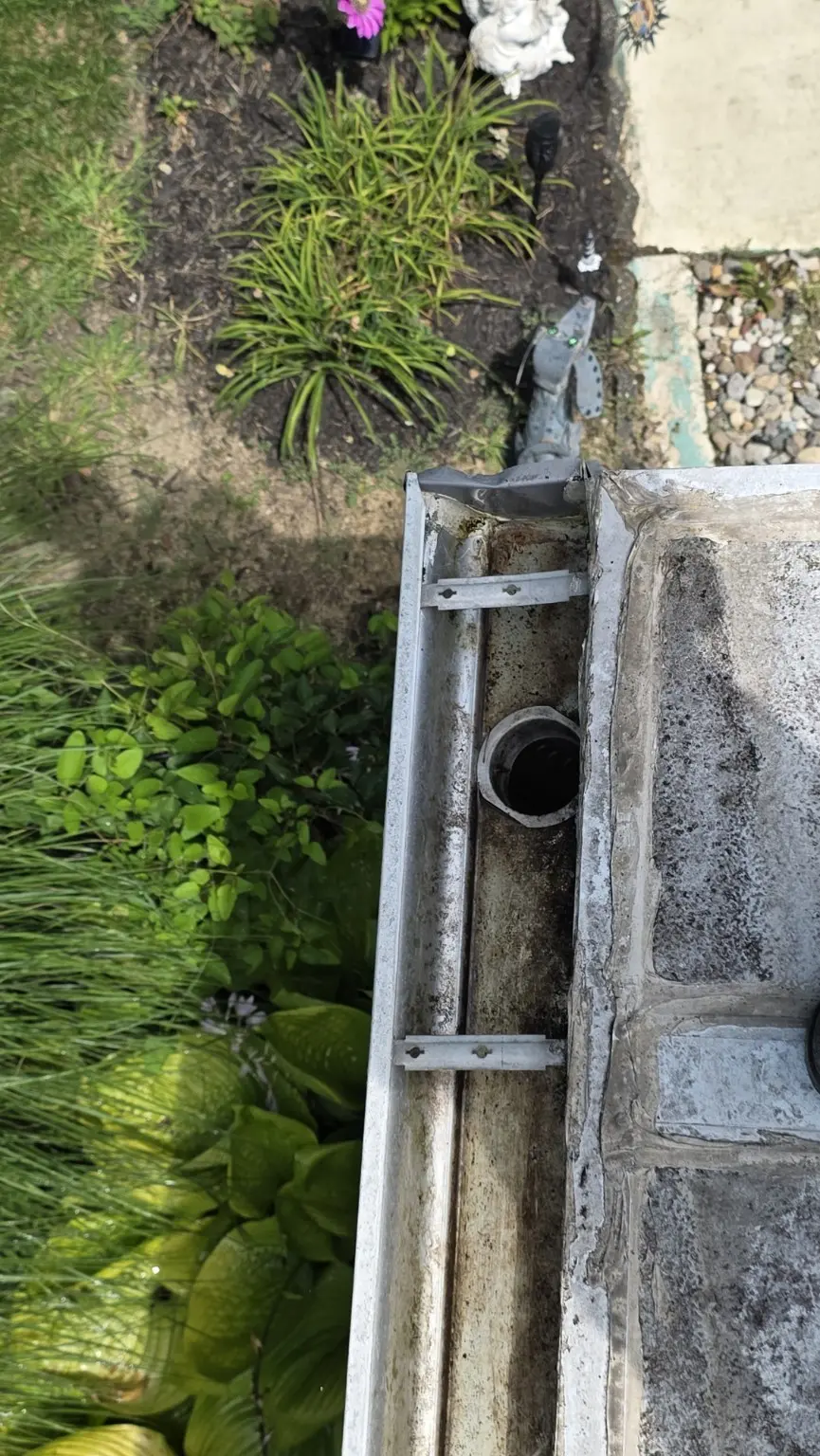 Close view of a cleared gutter outlet where water enters the downspout