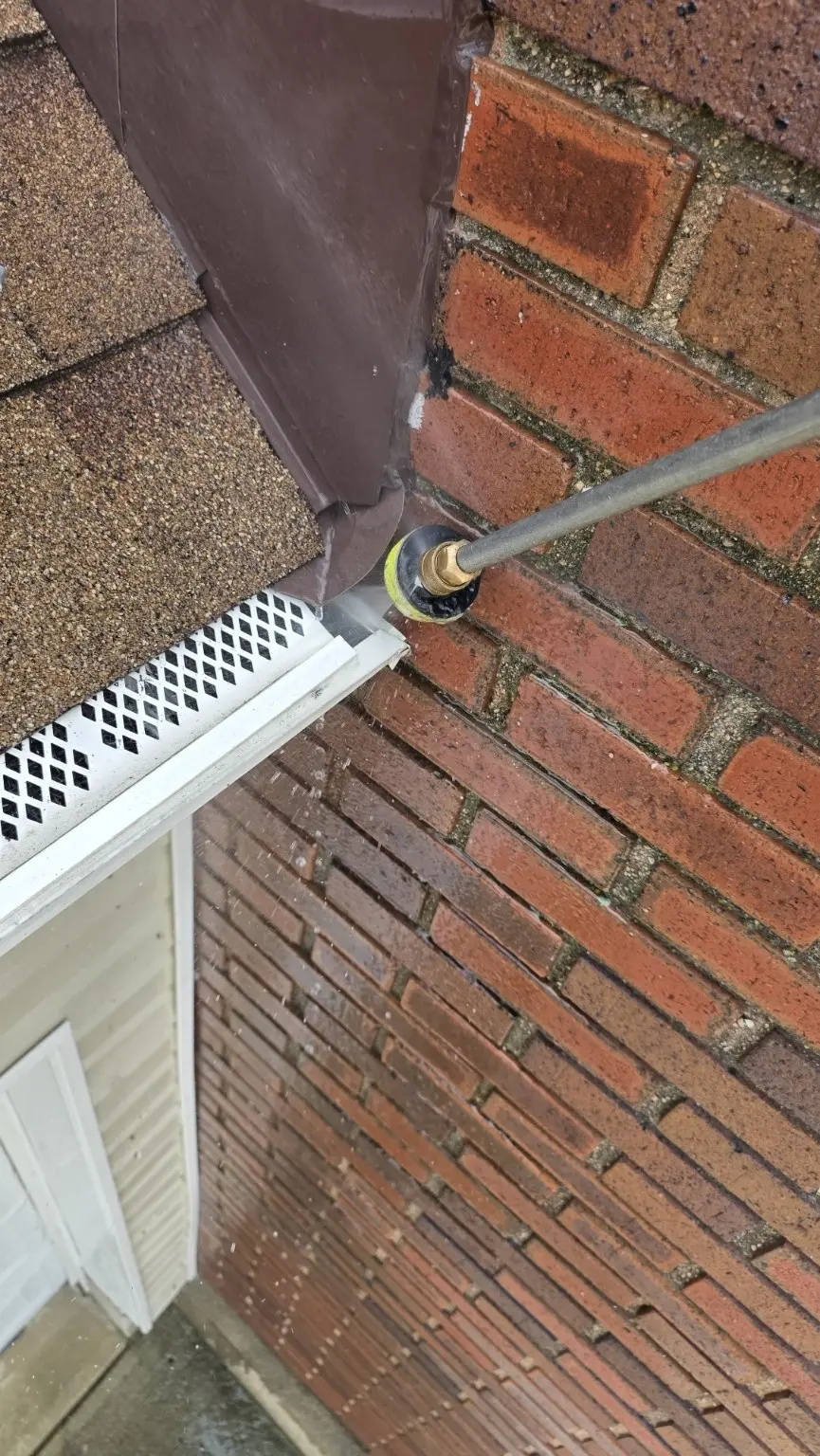 CleanFlow of Ohio cleaning and flow-testing a covered gutter at a tight roof and brick intersection