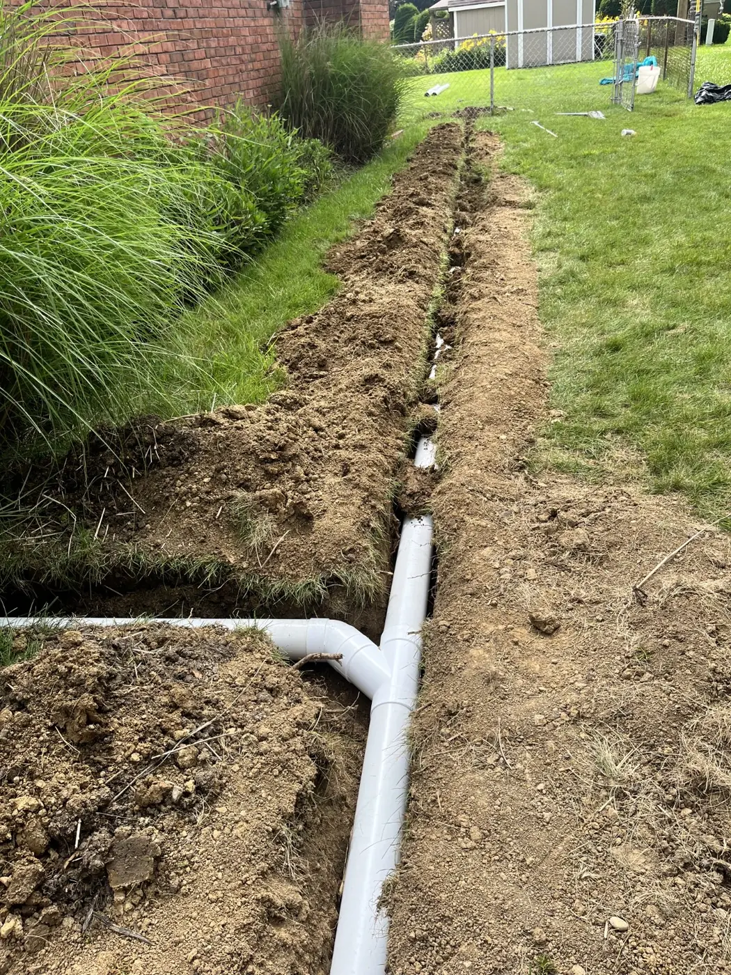 Solid PVC underground drainage line and branch connection installed in a residential trench
