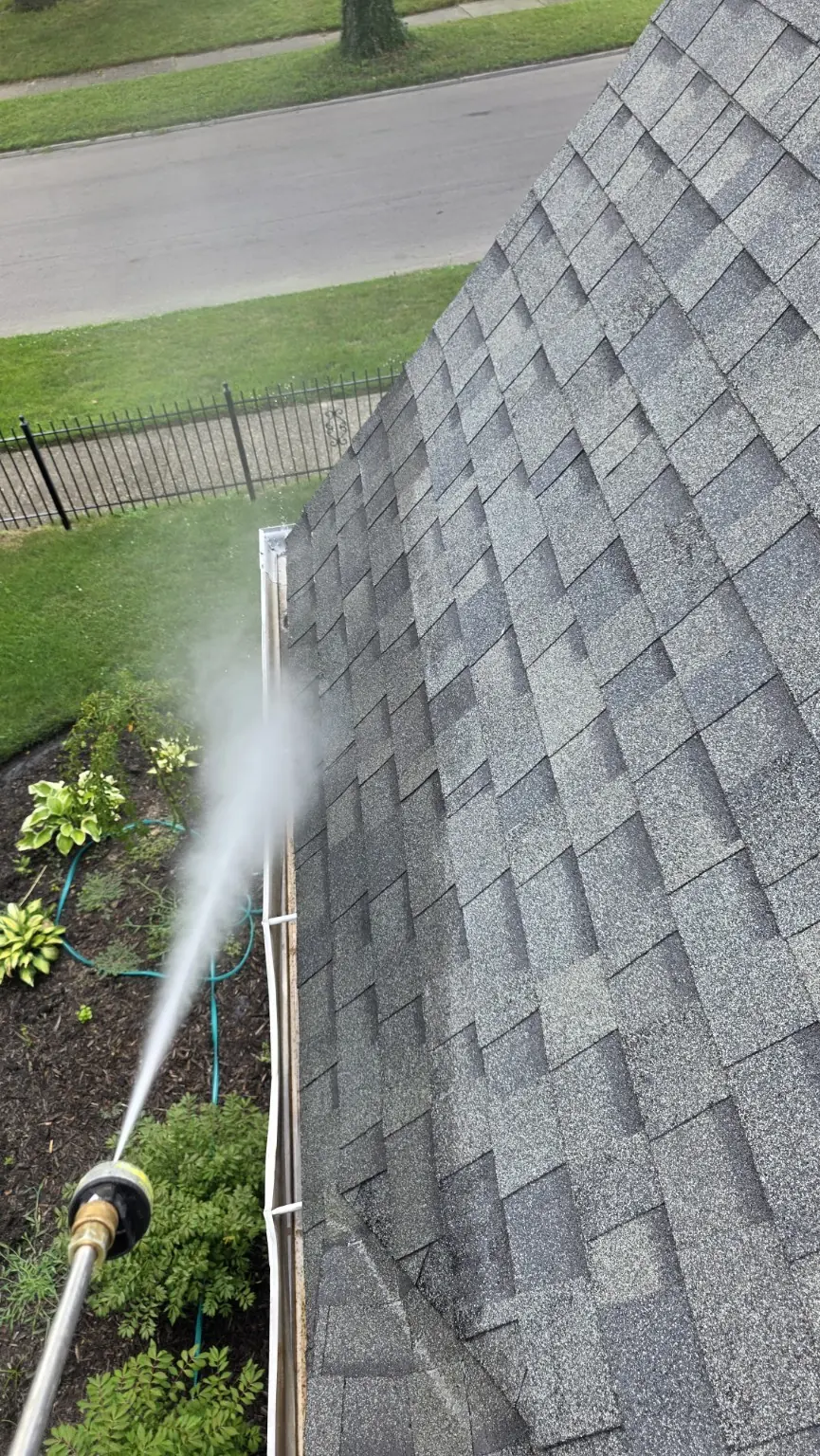 Water spray cleaning the exterior face of a residential gutter