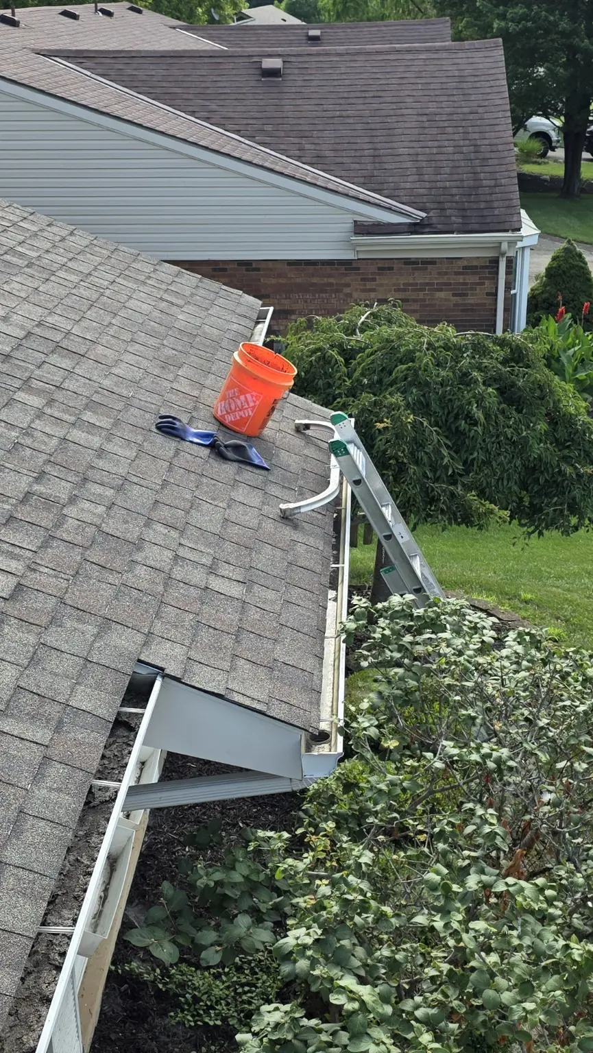 Bucket and ladder positioned beside an open gutter during a CleanFlow gutter cleaning visit