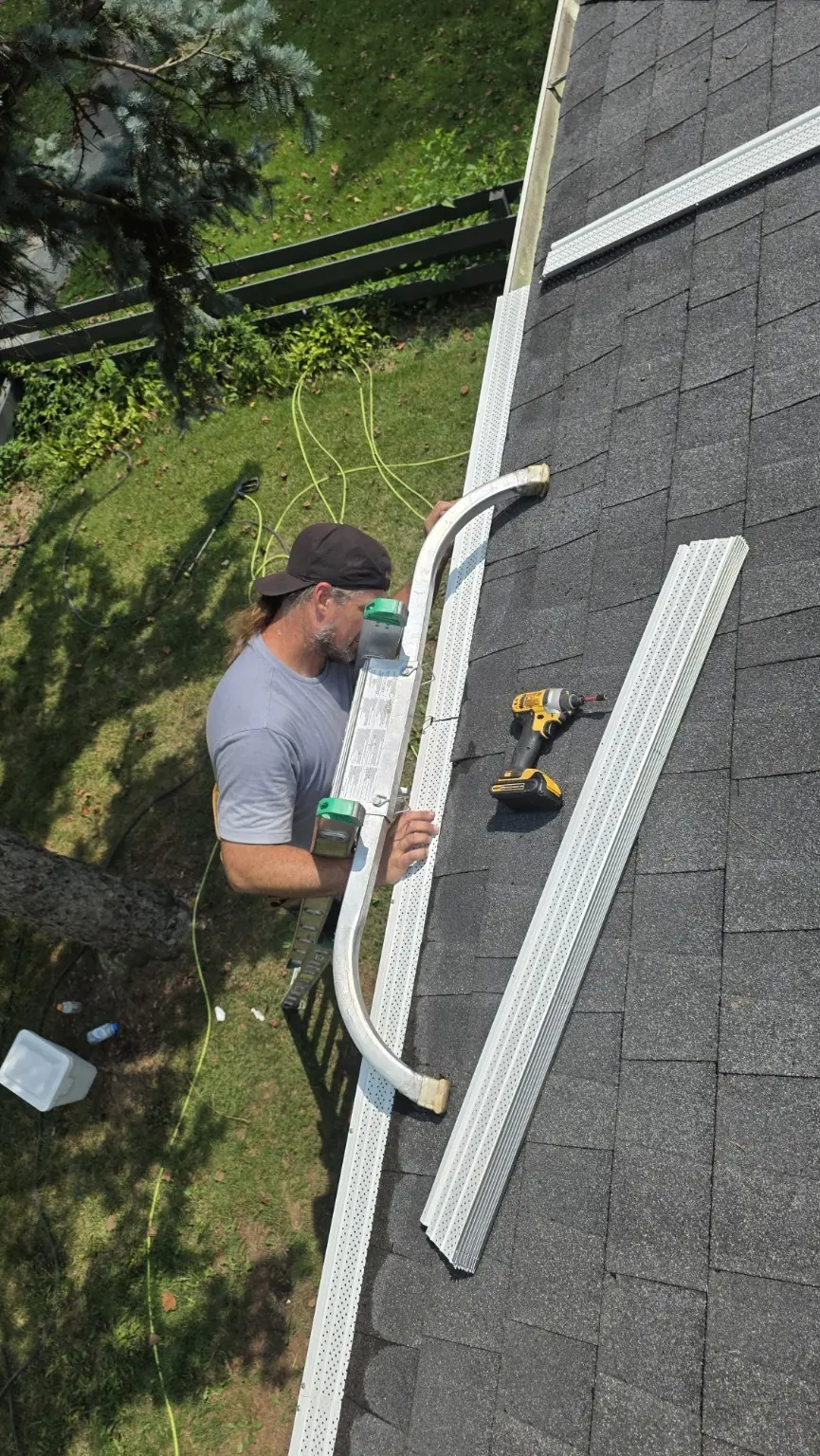 CleanFlow installer securing perforated aluminum gutter guards along a residential roofline