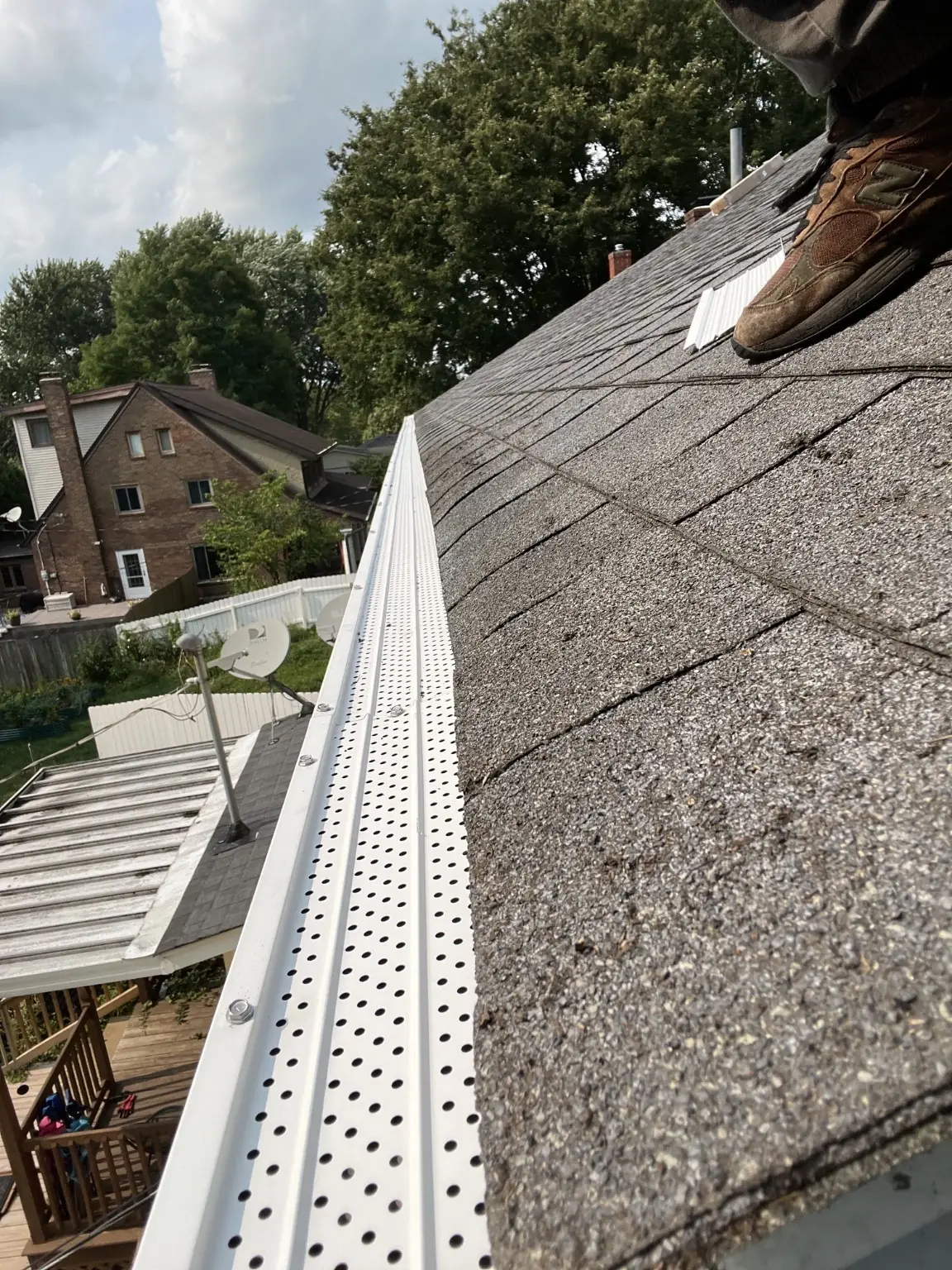 Finished perforated aluminum gutter guards secured along a residential roofline
