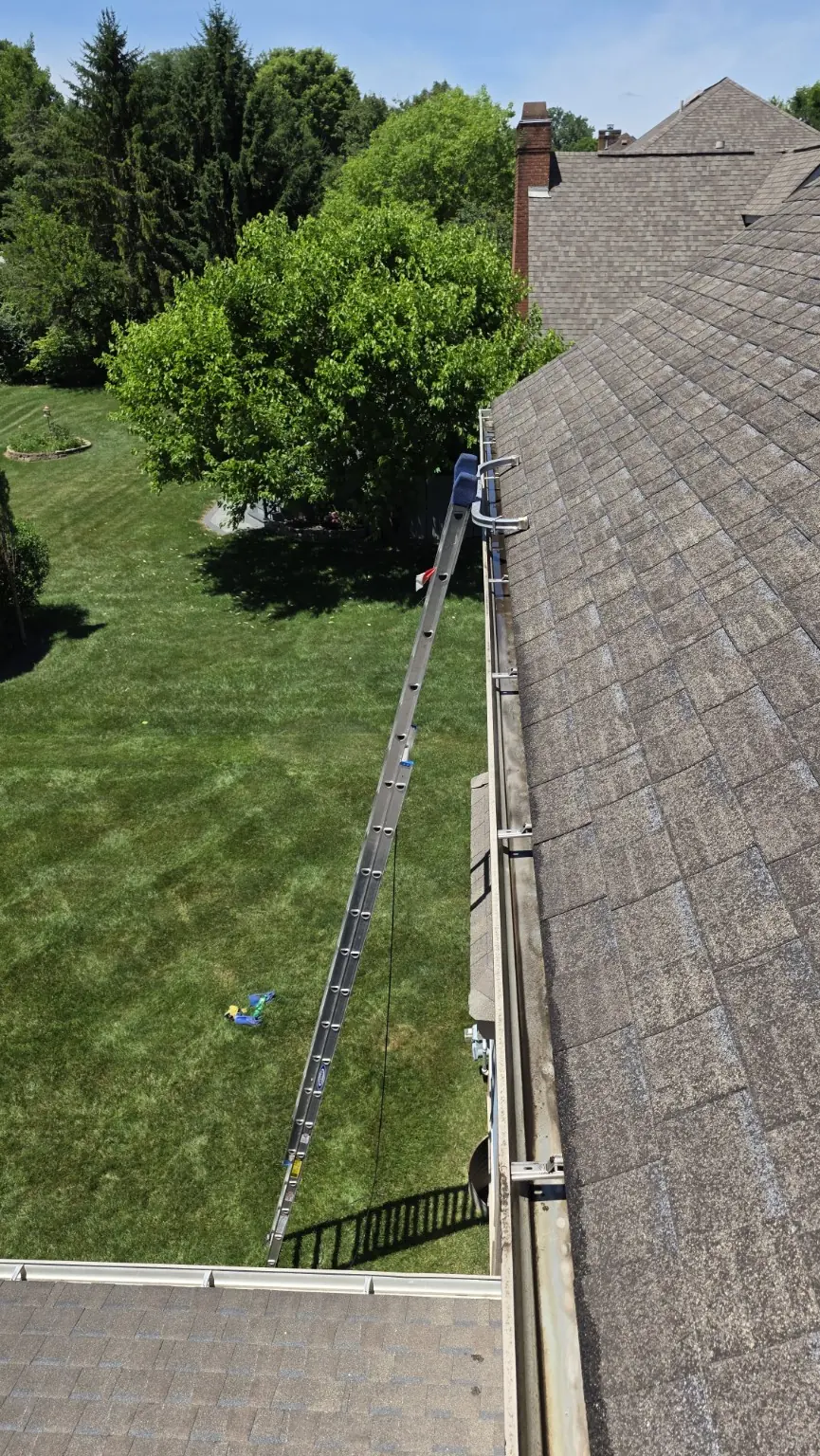 Extension ladder with a roof stabilizer positioned at the gutter line during a CleanFlow of Ohio service visit