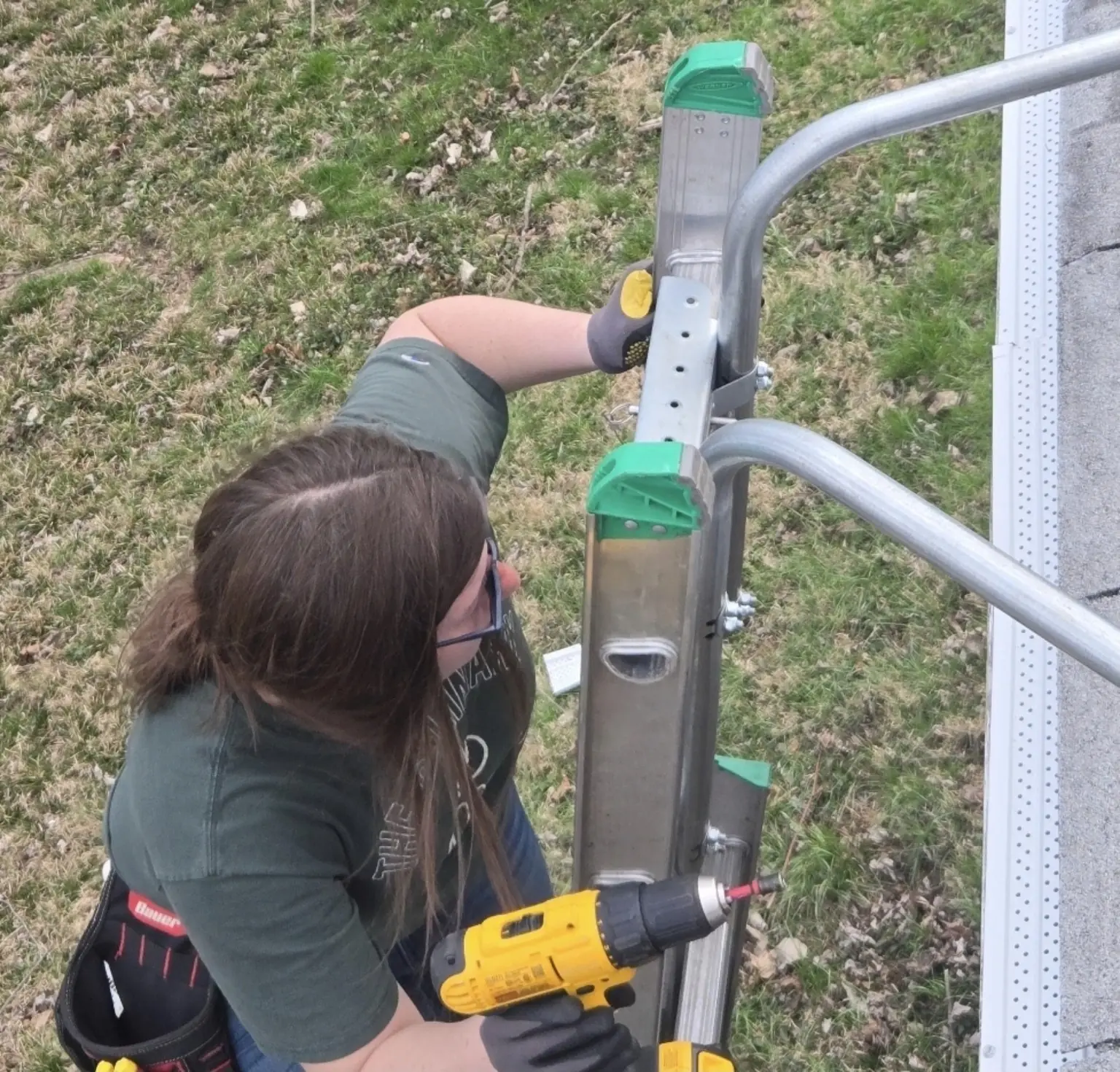 CleanFlow team member completing gutter repair work from a stabilizer-equipped ladder